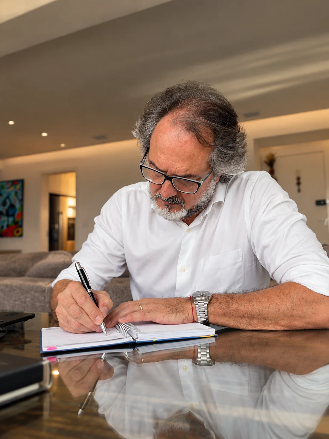 Guillermo Colombo sentado à mesa, escrevendo em um caderno
